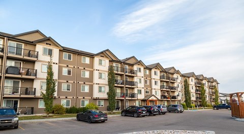 A large apartment building with cars parked in front.