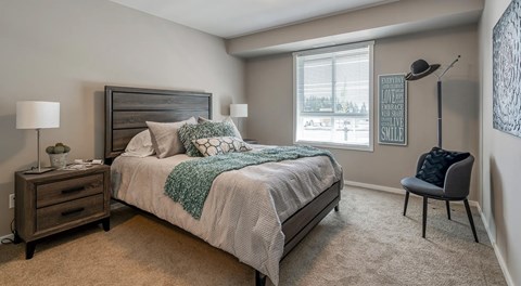 A bedroom with a bed, nightstand, and chair.