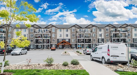 A large apartment complex with a parking lot in front.