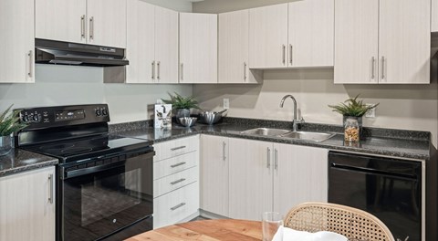A modern kitchen with black appliances and white cabinets.