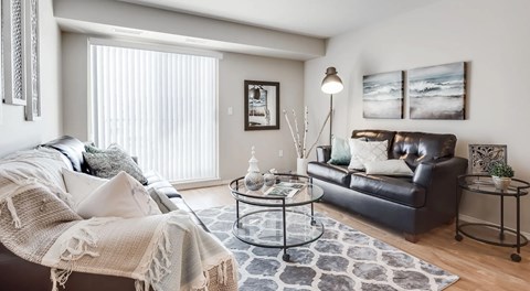 A living room with two couches and a coffee table. A large glass sliding door leads to a balcony
