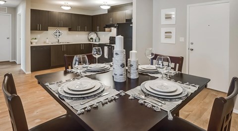An open kitchen with dark cabinets and black appliances with a table set for four