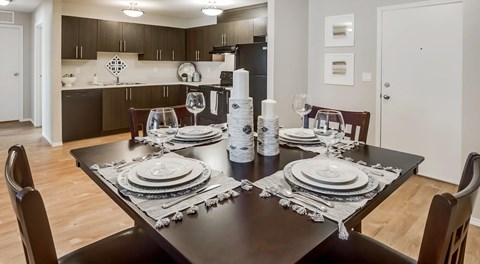 A large open kitchen space with dark cabinets, black appliances and a kitchen table set for four