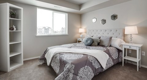A bedroom with a large bed, a nightstand, book shelf and large window