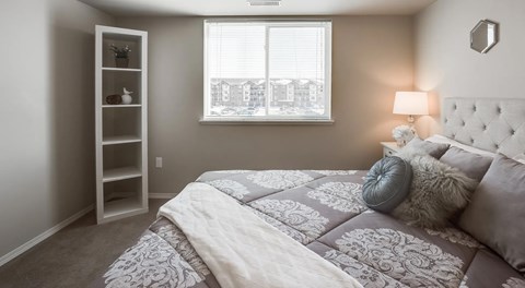 A bedroom with a large bed and a window with blinds.