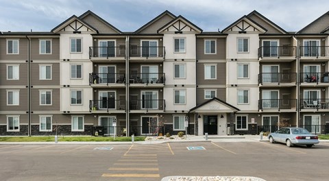 A large apartment complex with a parking lot in front.