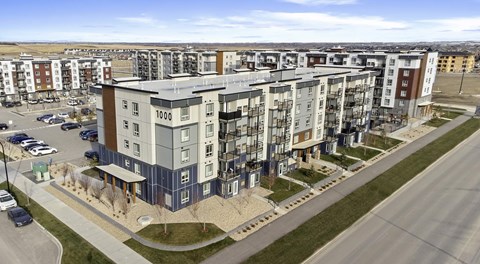 A five storey apartment building with landscaping out front and parking in behind