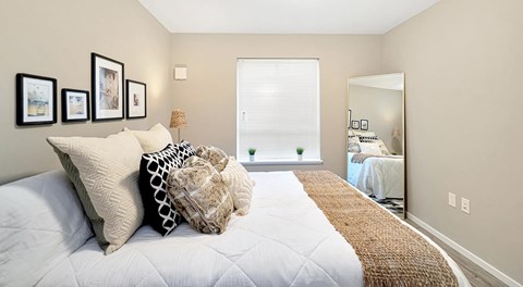 A bedroom, with queen sized bed, floor length mirror and window