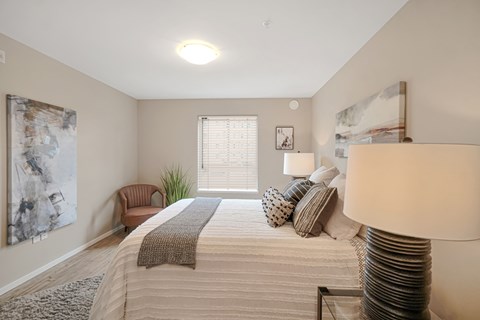 A well-lit bedroom with a large bed and a chair.