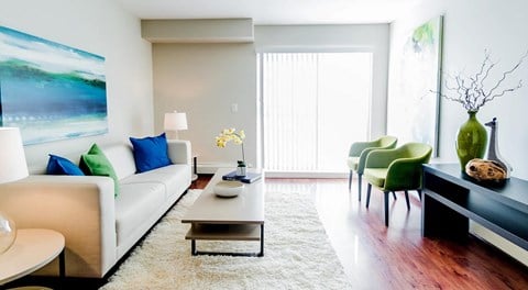 A living room with a white couch, chairs, coffee table and large glass sliding chair