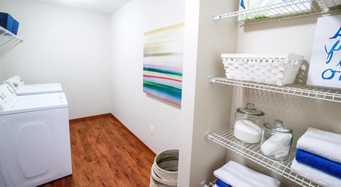 A laundry room with washer, dryer and a wall with shelving for storage