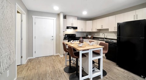 A modern kitchen with light cabinets, black appliances and a rectangular table