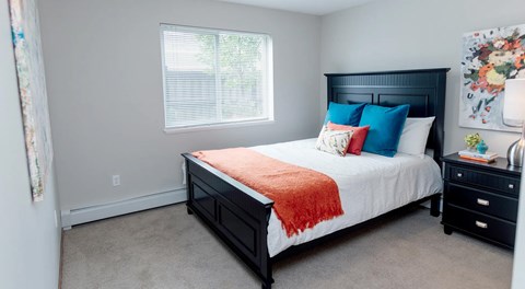 A bedroom with a bed, nightstand, and window.
