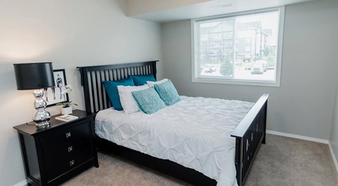 A bedroom with a bed, nightstand, and window.