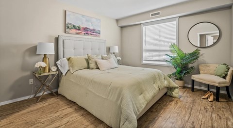 A bedroom with a large bed, a chair, and a window