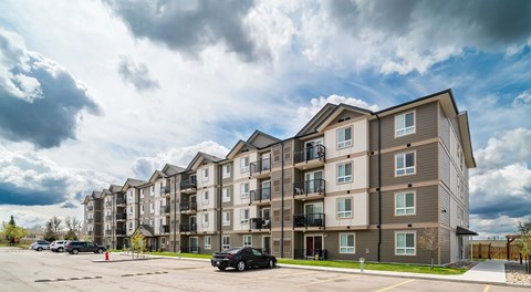 A large apartment complex with a parking lot in front.