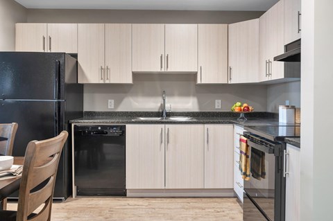 A kitchen with a black refrigerator and white cabinets.