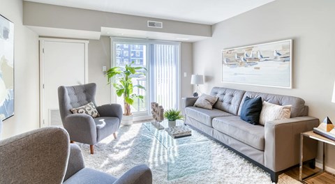 A bright living room with sliding door, large couch and chairs