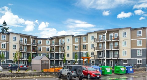 A large apartment building with parking, and community garden in front