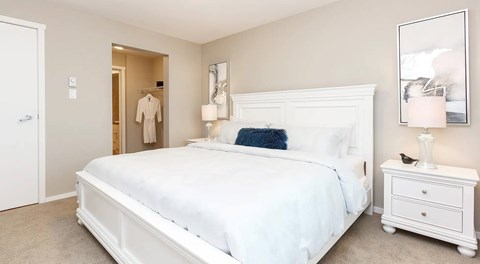 A queen sized bed with night stands, a walk in closet and ensuite