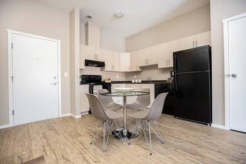 A kitchen with a black refrigerator and a table with chairs.