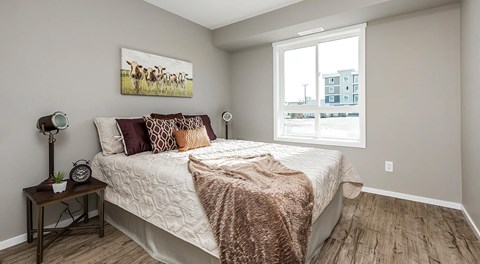 A bedroom with a queen sized bed and two night stands, with a large window