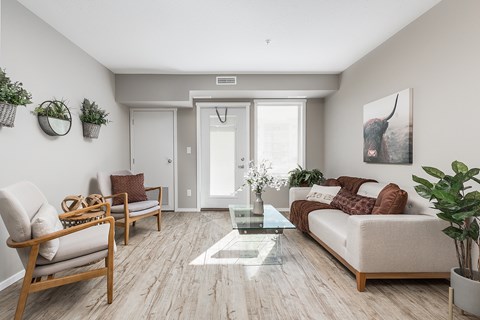 A living room with a couch, chair, and a painting of a cow on the wall.