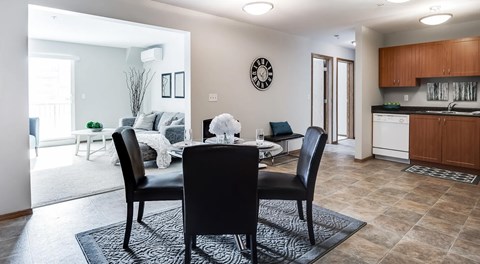 A dining area with round table set for four, opens to a kitchen on the right and a living room on the left