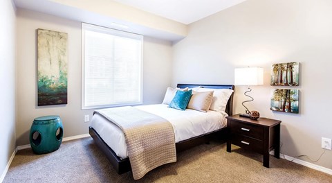 A bedroom with a bed, nightstand, and large window