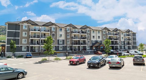 A large apartment building with a large parking lot out front