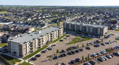 A large apartment complex with a parking lot in front.
