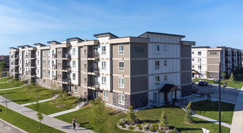 A large apartment building with green space in front
