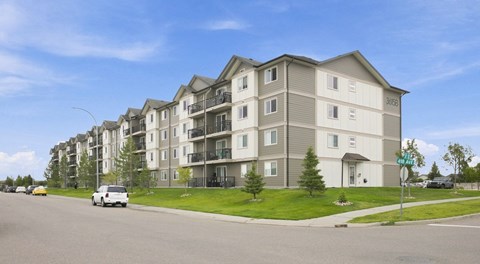 Four storey apartment building with street parking in front.