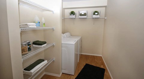 A laundry room with washer and dryer, a nook with multiple wire shelves for storage