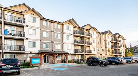 Apartment complex with cars parked in front.