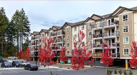An apartment building with covered parking at ground level along with uncovered parking