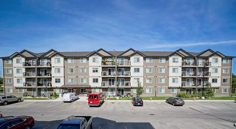 A large apartment complex with a parking lot in front.