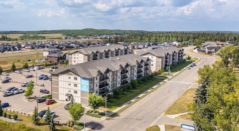A large apartment complex with a parking lot in behind and street parking out front