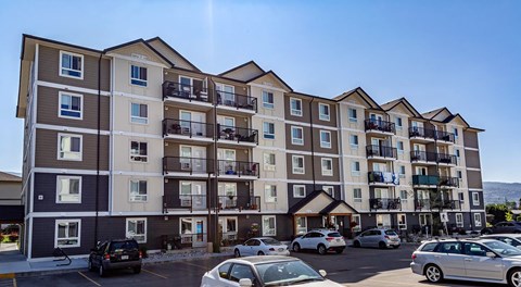 A large apartment building with a parking lot in front
