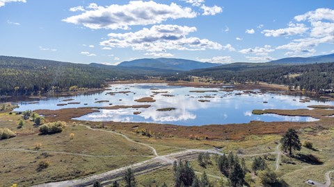 A scenic view of a lake surrounded by mountains and trees.