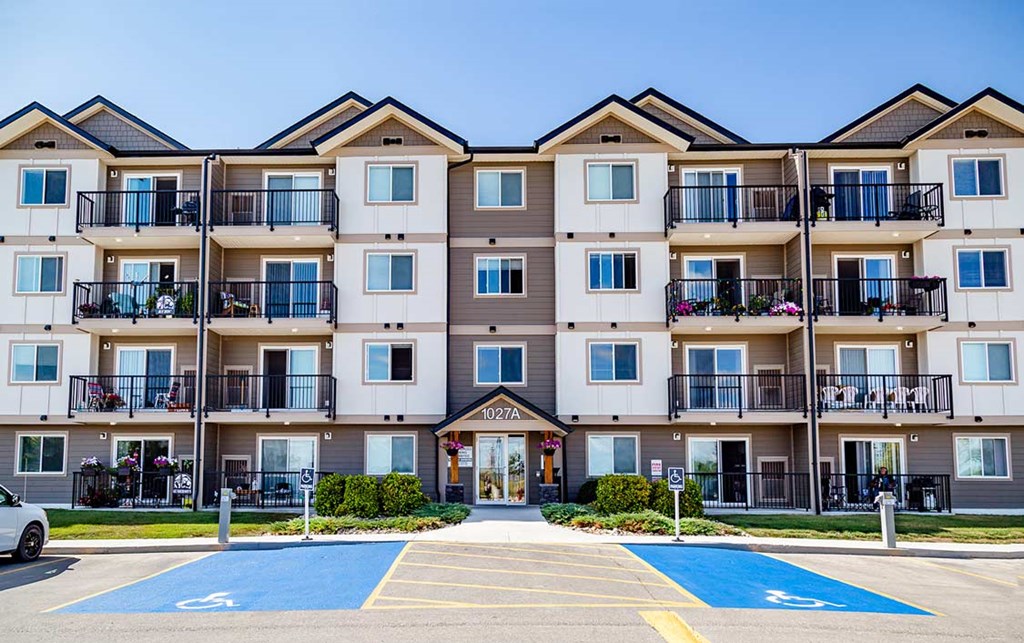 A large apartment complex with a parking lot in front.