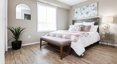 A bedroom with a queen sized bed,  night stands and large window