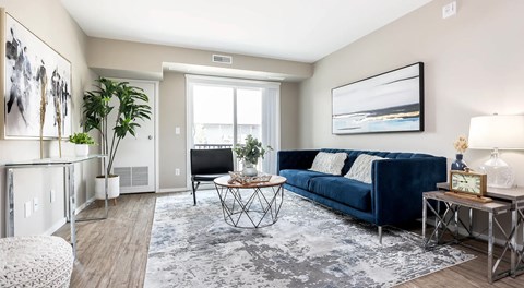 A apartment living room with a couch, chair and coffee table next to a large glass sliding door
