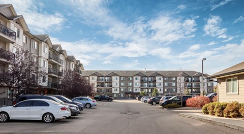 A large apartment complex with parking lot in front