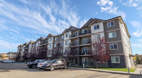 A large apartment building with a parking lot in front of it.