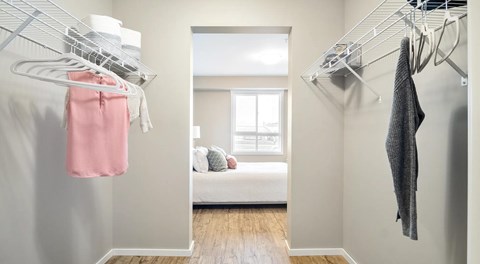 A walk in closet with wire shelving on both sides to hang clothing
