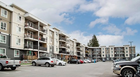 A large apartment building with four storeys, a large parking lot in front