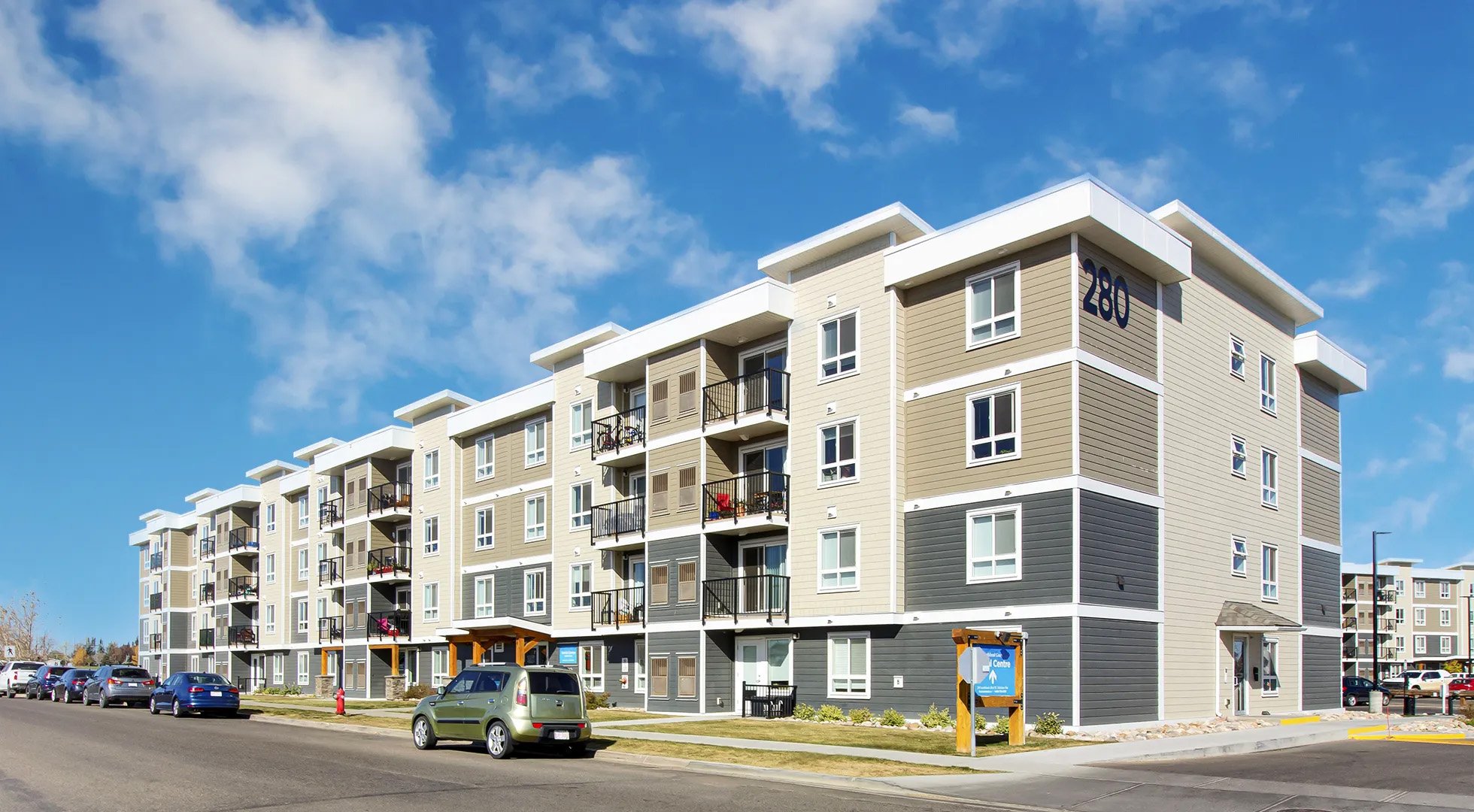 A four storey apartment building with street parking out front