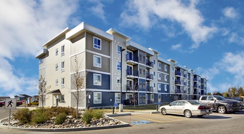 A modern apartment building with a parking lot in front.