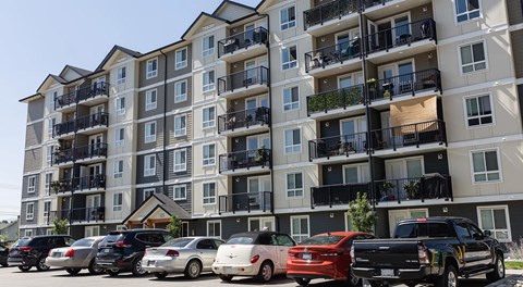 A large six storey apartment building with cars in front